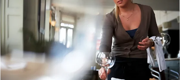 Una sonriente camarera prepara una mesa para los cientes